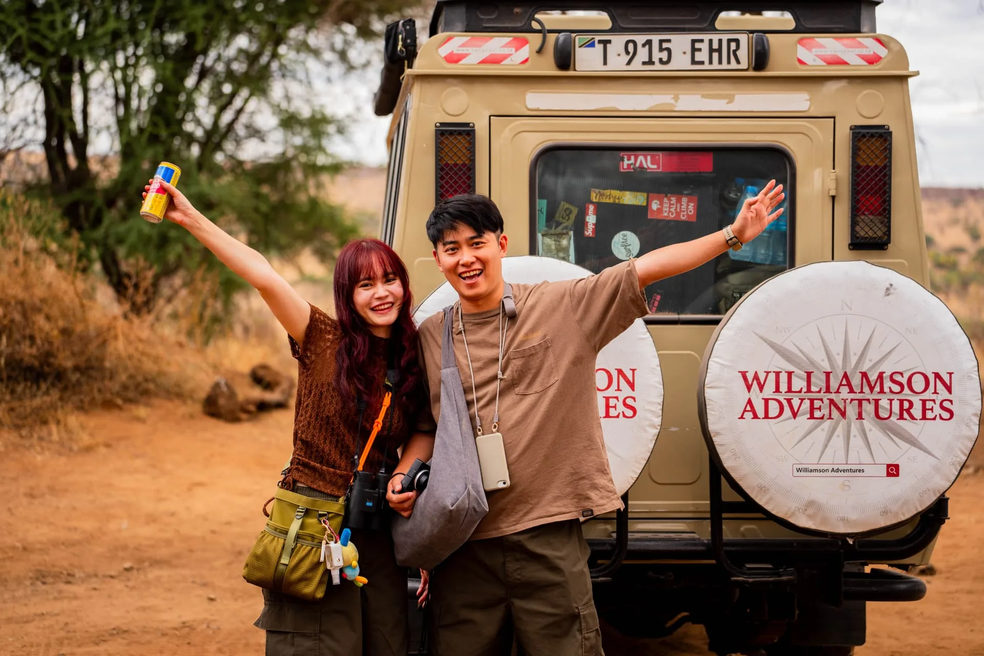 Happy guests beside a Williamson Adventures safari vehicle in Tanzania