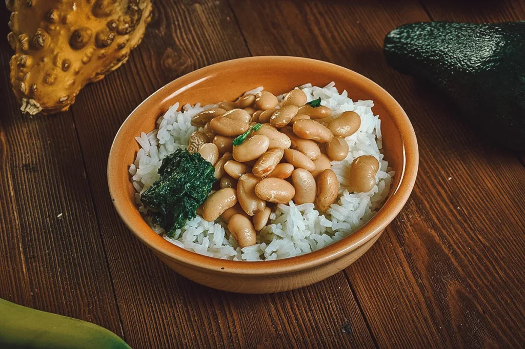 The humid air of Dar es Salaam carries a distinct perfume of charcoal smoke and roasting meat, an aromatic signal that you have arrived in a major culinary crossroads. While the Serengeti draws crowds for wildlife, the nation’s kitchen offers an equally impressive blend of tribal traditions and international influences. This rich tapestry makes traditional Tanzanian food a hidden gem within the broader landscape of East African cuisine. Just as pasta defines Italy, Ugali serves as the unshakeable foundation of the daily diet here. Think of this dense maize porridge as the "polenta of Africa"—a neutral, starchy canvas designed to scoop up spicy stews and savory greens. Common practice dictates that a meal is rarely complete without the "Big Three" staples of Ugali, rice, and beans, which provide sustenance across both city streets and rural villages. Exploring further reveals a distinct flavor split between the spice-laden coast and the hearty mainland. While island dishes in Zanzibar rely on creamy coconut milk and cloves, inland local food favors grilled meats and earthy grains. Mastering these basic distinctions allows you to navigate menus with confidence, transforming a simple dinner into a genuine cultural connection. Why Ugali is the Unifying Soul of the Tanzanian Plate If you expect a loose porridge like southern grits, the density of genuine Tanzanian Ugali will be a surprise. It functions less like a side dish and more like an edible spoon, boasting a dough-like consistency similar to stiff Italian polenta. This structural integrity is crucial because it allows the diner to pinch off a piece and scoop up sauces without the mash disintegrating, acting as the perfect neutral canvas for spicy stews or grilled meats. Achieving this specific firmness requires a vigorous workout during preparation. To replicate it at home, you can try substituting maize flour with fine white cornmeal, following three distinct stages: Boil: Bring water to a rolling boil before adding flour gradually. Stir: Mix continuously with a heavy wooden spoon to prevent lumps until a thick paste forms. Pound: Press the mixture forcefully against the pot's sides to cook out the raw starch before shaping it into a round mound. While Ugali dominates the dinner table, lunch often features a different, yet equally vital pairing: Wali na Maharage. This simple combination of fluffy white rice and red kidney beans stewed in coconut milk offers more than just comfort; the nutritional benefits stem from combining grains and legumes to create a complete protein source essential for fueling daily life. The creamy richness of the coconut reduction transforms humble pantry staples into a savory, satisfying meal that rivals any meat dish. Once you have mastered these mainland foundations, the culinary journey moves toward the coast, where simple grains are elevated by a complex history of trade. The Secret of the Spice Islands: Crafting Authentic Swahili Pilau If Ugali is the mainland's canvas, Pilau is the coast's vibrant masterpiece. This one-pot marvel traces the historical origins of Zanzibar's cuisine, where ancient trade winds brought bold flavors to East African shores. Unlike the wet, layered preparation of Biryani, Pilau involves cooking rice directly in a seasoned meat broth, allowing every grain to absorb the savory stock. The result is a dry, fluffy texture similar to a Middle Eastern plov, but with a significantly more aggressive aromatic profile. The dish's defining deep, golden-brown hue is achieved not through expensive saffron, but by carefully caramelizing onions and frying the spices until dark. To replicate authentic Swahili spice blends at home, you must move beyond generic curry powders and master the "Big Five" whole spices: Cloves (the signature scent of Zanzibar) Cardamom pods Cinnamon sticks Black peppercorns Cumin seeds Toasting these aromatics in hot oil releases a fragrance that highlights the deep Indian influence in Swahili cooking, blending Asian techniques with African produce. While Pilau is rich enough to stand alone, it is rarely served in isolation; on festive occasions, it acts as the aromatic partner to the country's other obsession—flame-grilled meats. Beyond the Grill: The Smoky Allure of Nyama Choma and Mshikaki If you follow the smoke rising from any Tanzanian backyard on a weekend, you will find the nation’s most beloved ritual: Nyama Choma. Translating simply to "roasted meat," this mainland staple focuses on letting the natural flavor of the protein—typically goat—shine through. Unlike complex coastal stews, authentic preparation is deceptively simple, relying on slow-roasting salted cuts over charcoal until the fat renders into a chewy, smoky delicacy that is traditionally pulled apart by hand. For travelers seeking bolder flavors, street vendors offer Mshikaki, the East African answer to the shish kebab. While standard roast meat relies on salt, these beef skewers are defined by an aggressive marinade that tenderizes the tougher cuts found in local markets. A potent blend of ginger, garlic, and lime juice breaks down the fibers before grilling, ensuring the meat develops a spicy, caramelized crust while remaining juicy inside. Heavy proteins require balance, which arrives in the form of Kachumbari, a fresh tomato and onion salad similar to pico de gallo. This ubiquitous side dish provides a necessary acidic crunch to cut through the richness of the meat. The raw onions are often rinsed in salt water to tame their bite, clearing the palate for the next heavy hitter in Tanzanian cuisine: the oily, comforting indulgence of the french fry omelet. The Ultimate Comfort Food: Decoding the Chipsi Mayai Phenomenon In the bustling streets of Dar es Salaam, convenience is king, and nothing embodies this better than Chipsi Mayai. Literally translating to "chips and eggs," this french fry omelet is the ultimate late-night snack. Unlike slow-roasted meats, this savory creation represents the fast-paced energy of urban Tanzania, marrying Western ingredients with distinct local flair to create a dish similar to a Spanish tortilla, but with fried potatoes. Recreating this staple is effortless using a single pan. A standard recipe for beginners involves frying potatoes until crisp, then pouring whisked eggs directly over them to bind everything into a thick, golden disk. The result is a textural masterpiece where fluffy fries meet soft, savory egg curds, usually dipped in spicy chili sauce or ketchup for an added kick. While it resembles a simple junk food mashup, this dish is a serious contender for the national favorite. It offers a heavy, satisfying contrast to lighter local food options found near the ocean. This heartiness provides a perfect pivot toward the delicate, aromatic flavors awaiting in the region's famous coconut fish curries. Coastal Creaminess: Mastering Mchuzi wa Samaki Coconut Fish Curry Leaving the urban rush behind, the air shifts to carry the scent of ocean brine and simmering spices. On the coast, particularly in Zanzibar, the cuisine centers on Mchuzi, the Swahili word for stew or gravy. The crown jewel here is Mchuzi wa Samaki, a rich fish curry that trades heavy frying for slow-simmering depth. Think of it as a tropical bouillabaisse, but instead of a tomato base, it relies on the lush, silky texture of coconut milk to coat fresh snapper or kingfish. Creating a successful Mchuzi wa Samaki at home requires managing the delicate fats in the sauce. The secret is a gentle reduction: simmer the liquid uncovered on low heat to thicken it without curdling the milk. To cut through this richness, Swahili cooks masterfully balance the sweet coconut with these essential components: Fresh coconut milk for the creamy body Turmeric for earthy warmth and golden color Garlic for savory depth Tamarind (or lime) for necessary acidity Beyond its incredible flavor, this style of cooking leverages healthy coconut-based fats, which are a staple energy source in the coastal diet. While this curry represents the traditional, slow-food side of the islands, the local street food scene offers a much faster, chaotic energy. From Zanzibar Pizza to Ndizi Kaanga: The Street Snack Revolution If you order "pizza" in Stone Town, do not expect a Neapolitan pie with tomato sauce. The distinction between Zanzibar Pizza and traditional Italian pizza is structural; the Tanzanian version is actually a savory wheat envelope more akin to a stuffed crepe or murtabak. Vendors expertly stretch a ball of dough until it is translucent, fill it with minced meat, cheese, mayonnaise, and an egg, then fry the folded square on a hot griddle until the exterior is blistered and crisp. While savory dough rules the night markets, natural sweetness dominates the roadside grills. Mastering Tanzanian Ndizi Kaanga (fried plantains) requires selecting yellow plantains at peak ripeness, distinct from the starchy green Matoke bananas used in savory stews. These are sliced and deep-fried until the surface sugars caramelize, creating a chewy, golden exterior that contrasts with the meltingly soft fruit inside, often highlighted by a pinch of salt. For a texture that bridges the gap between a donut and a pancake, locals turn to Vitumbua. The signature fluffiness of these treats comes from the fermentation process, where a batter of rice flour, coconut milk, and yeast rests to develop active air pockets. This leavening creates a spongy, honeycomb interior that holds the warm aroma of cardamom and pairs perfectly with a cup of hot chai. Street food acts as the primary social connector in daily Tanzanian life, blurring the lines between quick sustenance and community gathering. This shared reliance on public vendors prepares a visitor for the broader rules of hospitality, specifically the communal etiquette that defines how Tanzanians approach the morning meal. The Social Ritual: Etiquette and What Tanzanians Eat for Breakfast Mornings typically start sweet rather than savory. Regarding what Tanzanians eat for breakfast, the most iconic pairing is Chai (tea simmered with ginger and spices) served alongside Mandazi. These triangular pastries resemble a Western donut but replace the heavy sugary glaze with subtle hints of coconut milk and cardamom, making them distinctively aromatic and perfect for dipping. As the day progresses to heavier meals, the focus shifts to shared platters. Understanding dining etiquette and customs ensures you show respect to your hosts, particularly regarding the strict "Right Hand Rule." Hand Washing: Wait for the host to bring a pitcher and basin to the table. Right Hand Only: Eat, pass, and accept food strictly with your right hand; the left is considered unclean. Communal Boundaries: Eat only from the portion of the shared plate directly in front of you. Elder Respect: Always wait for the oldest person at the table to take the first bite. Communal bowls often feature stewed beans (Maharage) or sautéed spinach (Mchicha), which are consistently the best dishes for vegetarians. These accessible staples prove that you do not need complex equipment to recreate the experience, setting the stage for bringing these East African flavors into your own kitchen. Your Map to the Tanzanian Table: Integrating Flavors into Your Kitchen You have journeyed from the hearty Ugali of the highlands to the clove-scented Pilau of the coast, gaining a true sensory understanding of Tanzania's traditional food. This knowledge transforms a menu into a cultural map, highlighting the specific coconut infusions and slow-cooked techniques that define the nation’s palate beyond general East African staples. This insight ensures you can spot the subtle differences between Tanzanian and Kenyan food, particularly the heavier coastal spice influence found in Tanzania. It also empowers you to recognize that savory bean stews and greens like Mchicha offer robust, naturally gluten-free flavors without relying on meat. Bring these flavors to life by hosting a mini tasting at home. Start by sourcing a Pilau spice blend or frying up Chipsi Mayai, then invite friends to share the meal communal-style. By taking that first bite, you bridge the gap between reading about Tanzania and experiencing its warm hospitality.